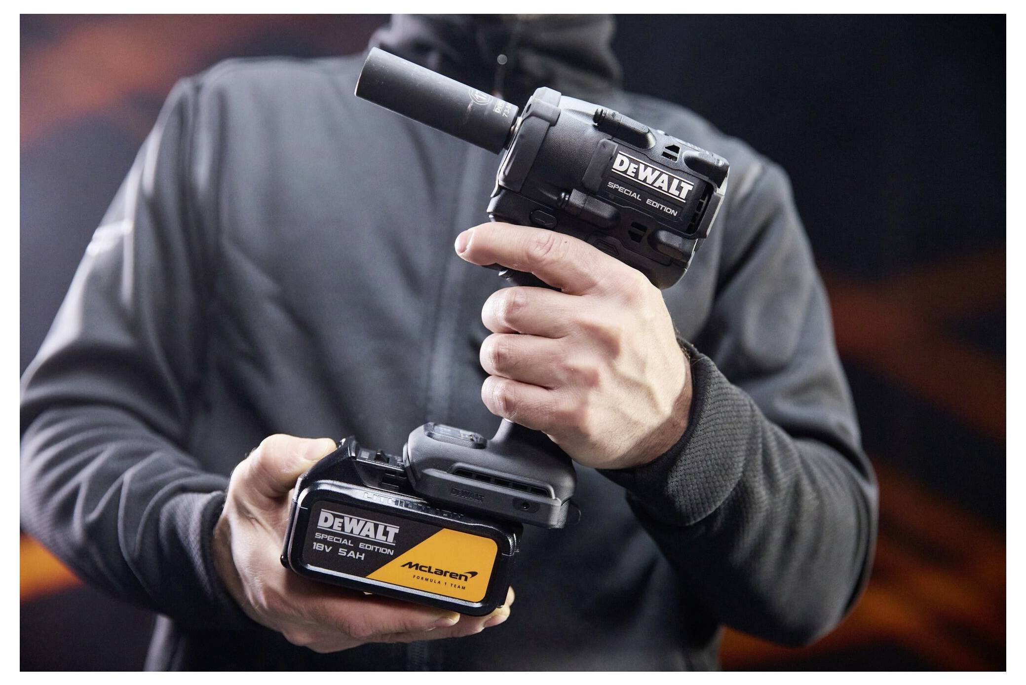Person som håller ett DEWALT trådlöst elverktyg och batteriladdningspack, visar verktyget och märkningen i närbild.