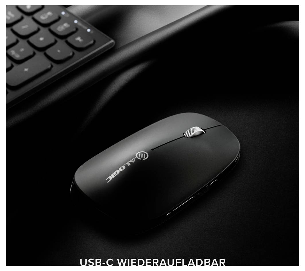 Svart trådlös mus på ett mörkt skrivbord bredvid ett tangentbord, med texten "USB-C WIEDERAUFLADBAR" som anger att den är uppladdningsbar via USB-C.