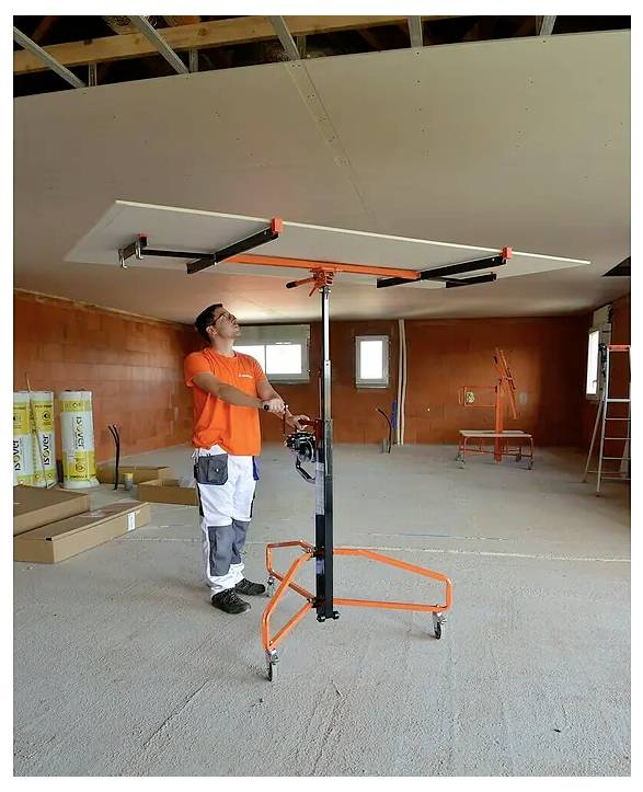 Byggarbetare i ett ofärdigt rum som använder en lyftställning för att hålla en stor takpanel overhead för installation.