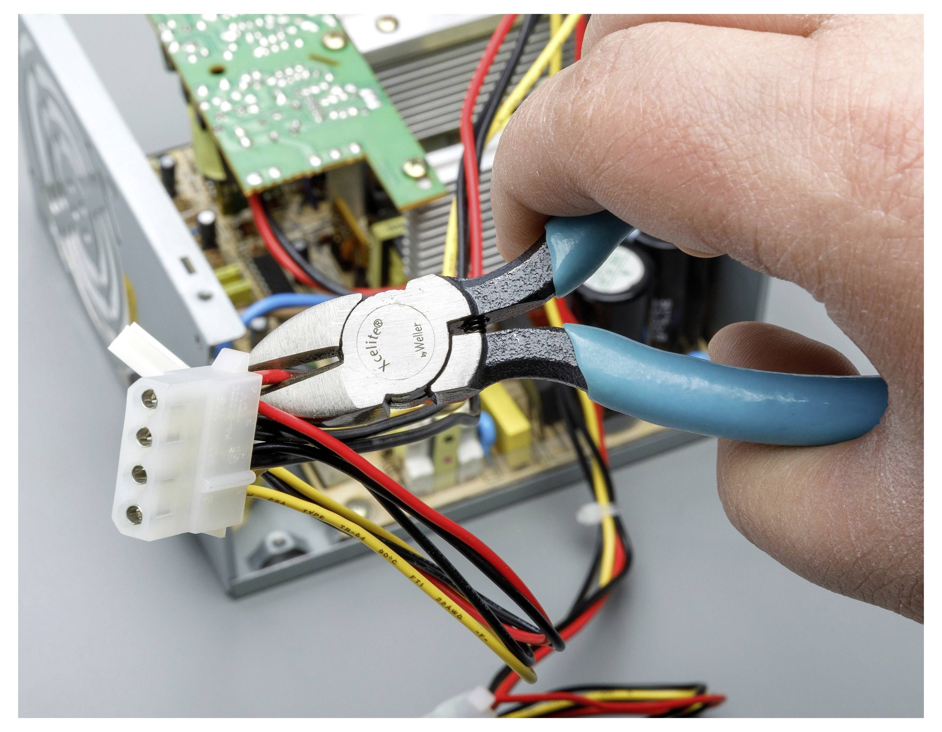 Hand som håller tänger för att klippa ledningar på en datorströmanslutare inuti en öppen elektronisk enhet.