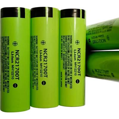 Fyra gröna NCR21700T litium-jon-battericeller, visade upprätt och staplade på sidan, med tryckt varnings- och modeltext.