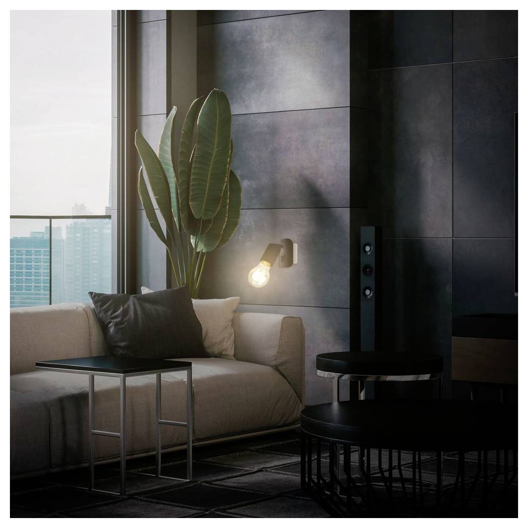 Modernt vardagsrum med beige soffa, svarta sidobord, högt växtarrangemang och exponerad glödlampvägglampa bredvid ett stort fönster.