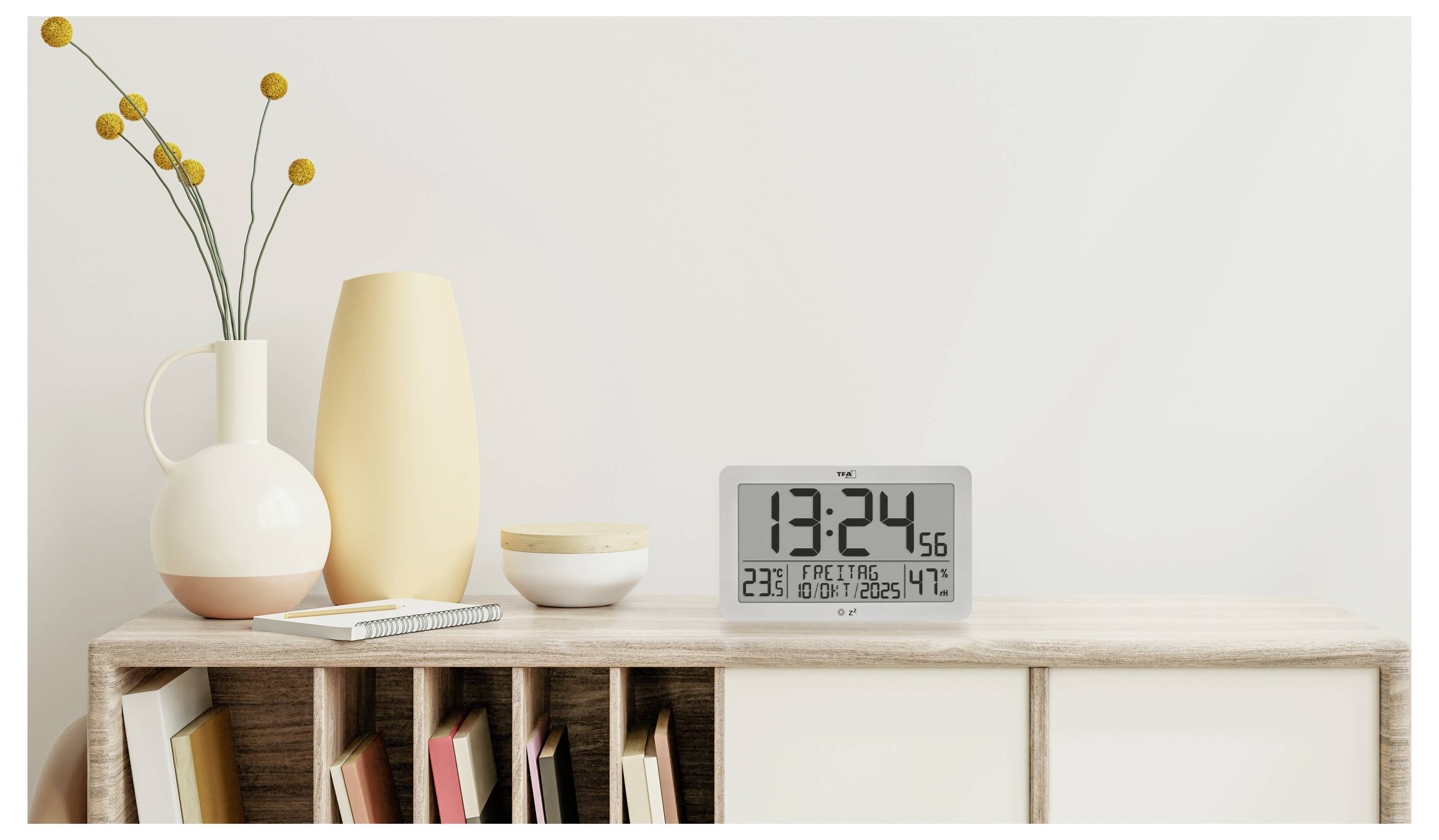 Minimalistisk skrivbord med böcker, vaser, blommor och en digital klocka som visar 13:24:56 med temperatur- och datumvisning.