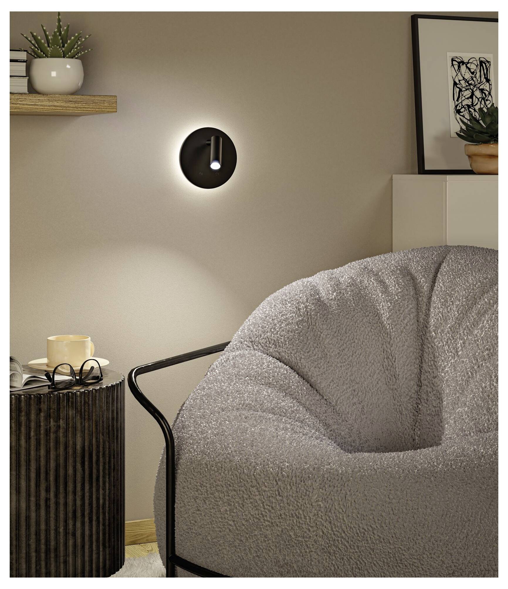 Mysigt hörn i sovrummet med en tänd vägglampa, grå boucléstol, sidobord, växthydda på hylla och inramad konst.