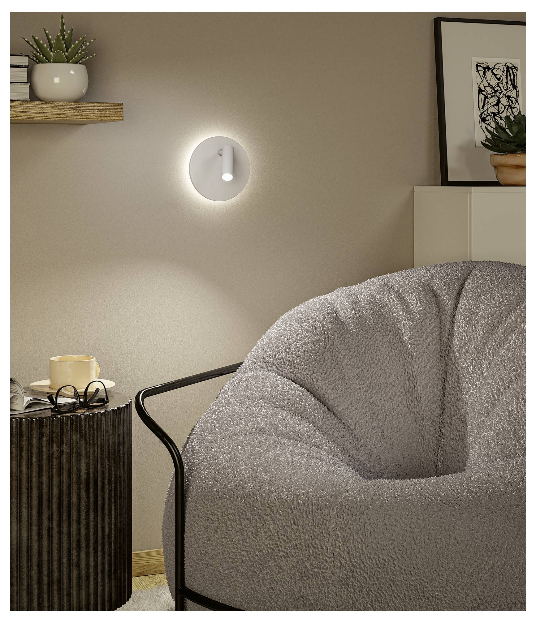 Mysig vardagsrumshörna med en glödande vägglampa, grå möbel med klädsel, sidobord med mugg och glas, och inramad konst.