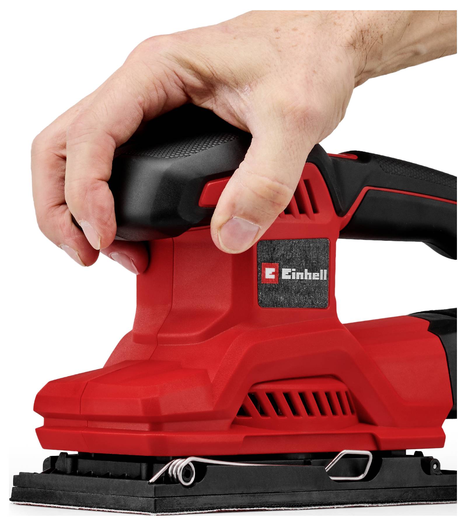 Hand som håller en röd-och-svart Einhell elsander på en vit bakgrund.