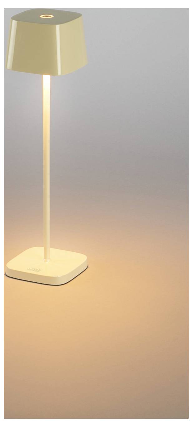 Moderne golvlampa med fyrkantig vit bas, slank stång och beige skugga som kastar ett varmt ljus på en ljus bakgrund.
