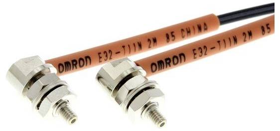 Två OMRON E32-T11N 2M B5 fiberoptiska sensorer med gängade metallkopplingar och orange kablar på en vit bakgrund