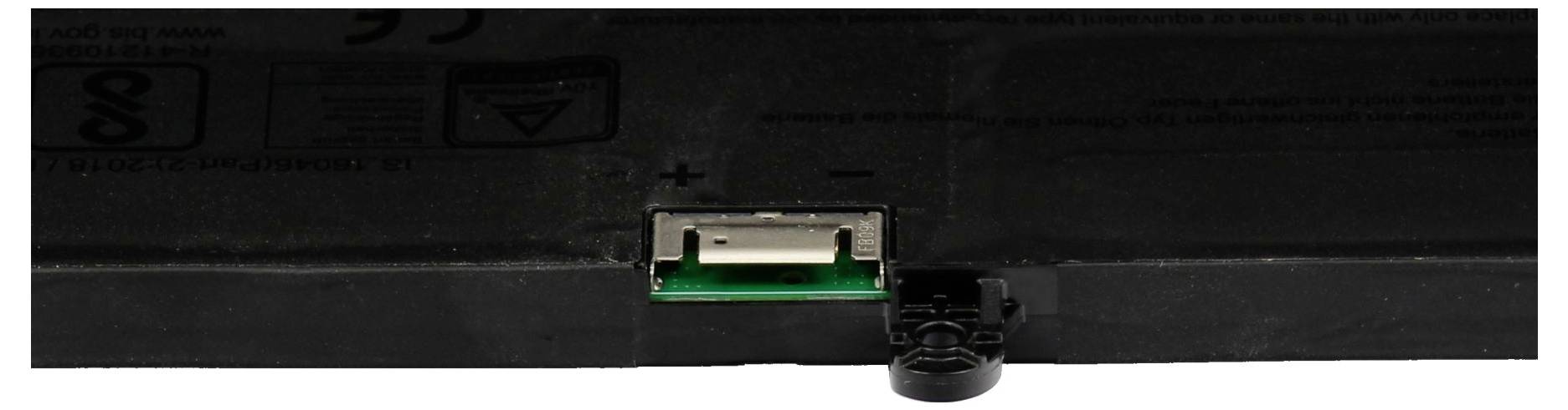 Närbild av en enhets bakre portpanel, som visar en centrerad vit USB-port och en närliggande svart kontakt mot ett mörkfärgat hölje.