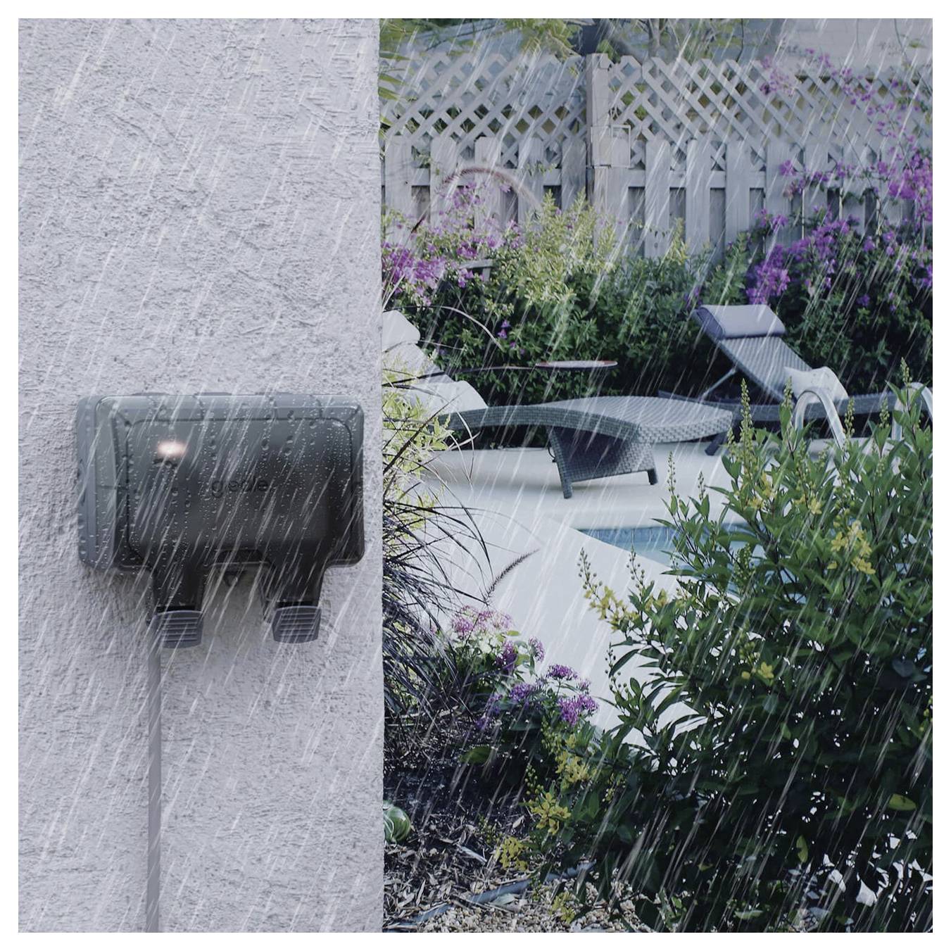 Regn som faller över en bakgård med uteplats, solstolar och växter; en väggmonterad utomhusarmatur är i förgrunden.