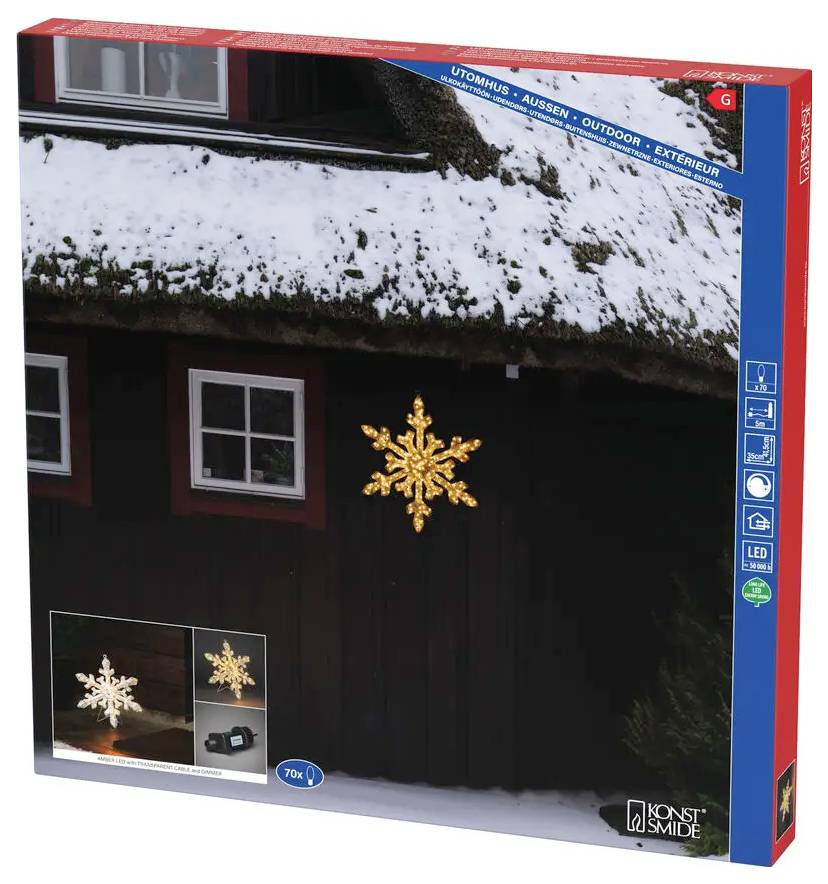 Box för en guldlysande LED-snöflakedekorationsverk, visad monterad på ett mörkt husfasad med snö på taket.