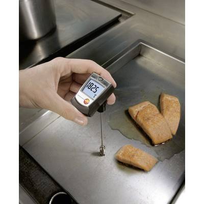 En hand håller ett köttermometer som visar en temperatur på 182,5 grader intill tre laxfiléer som ligger på en het stekpanna.