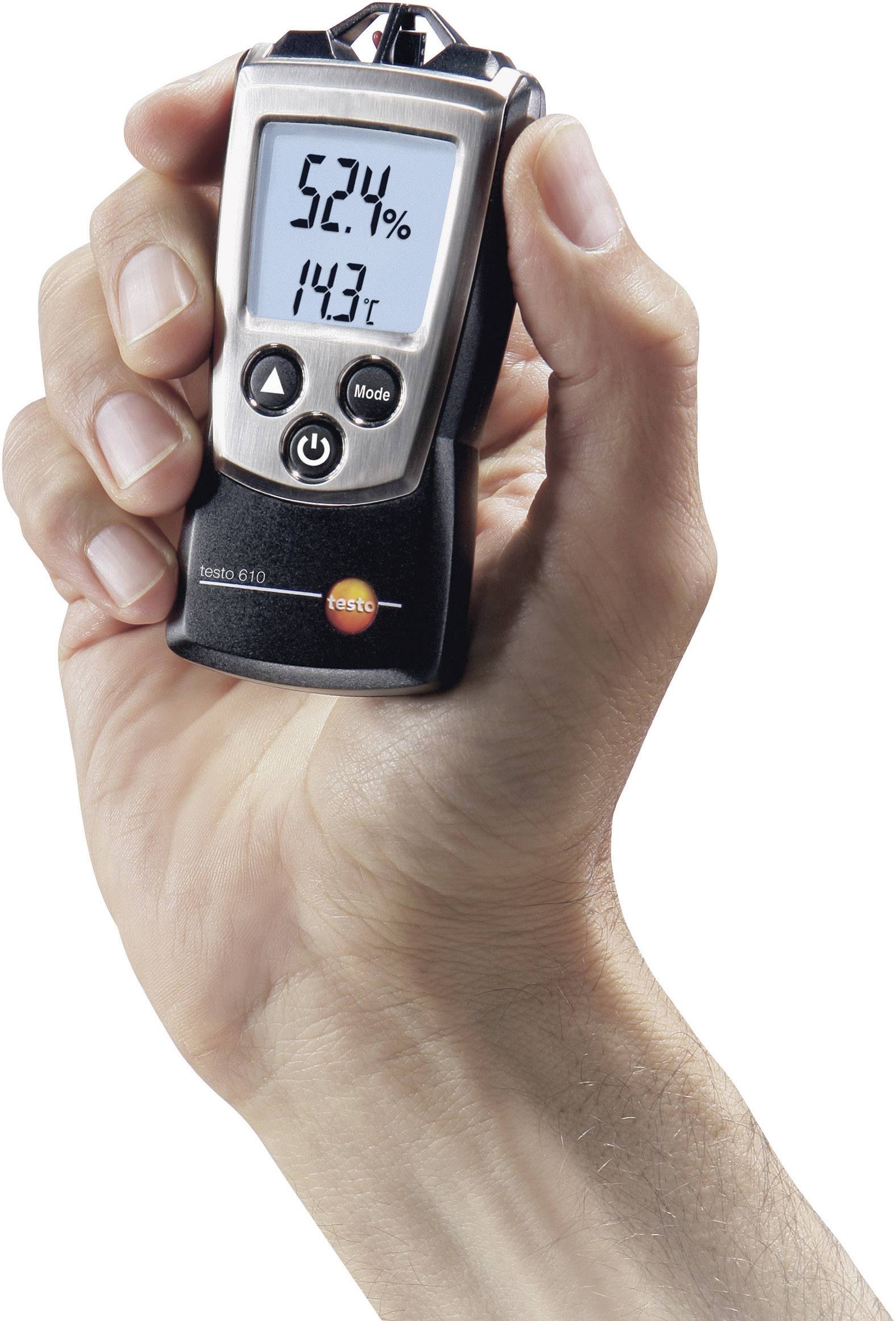 En hand håller ett digitalt hygrometer som visar 52,1% luftfuktighet och 14,3°C.