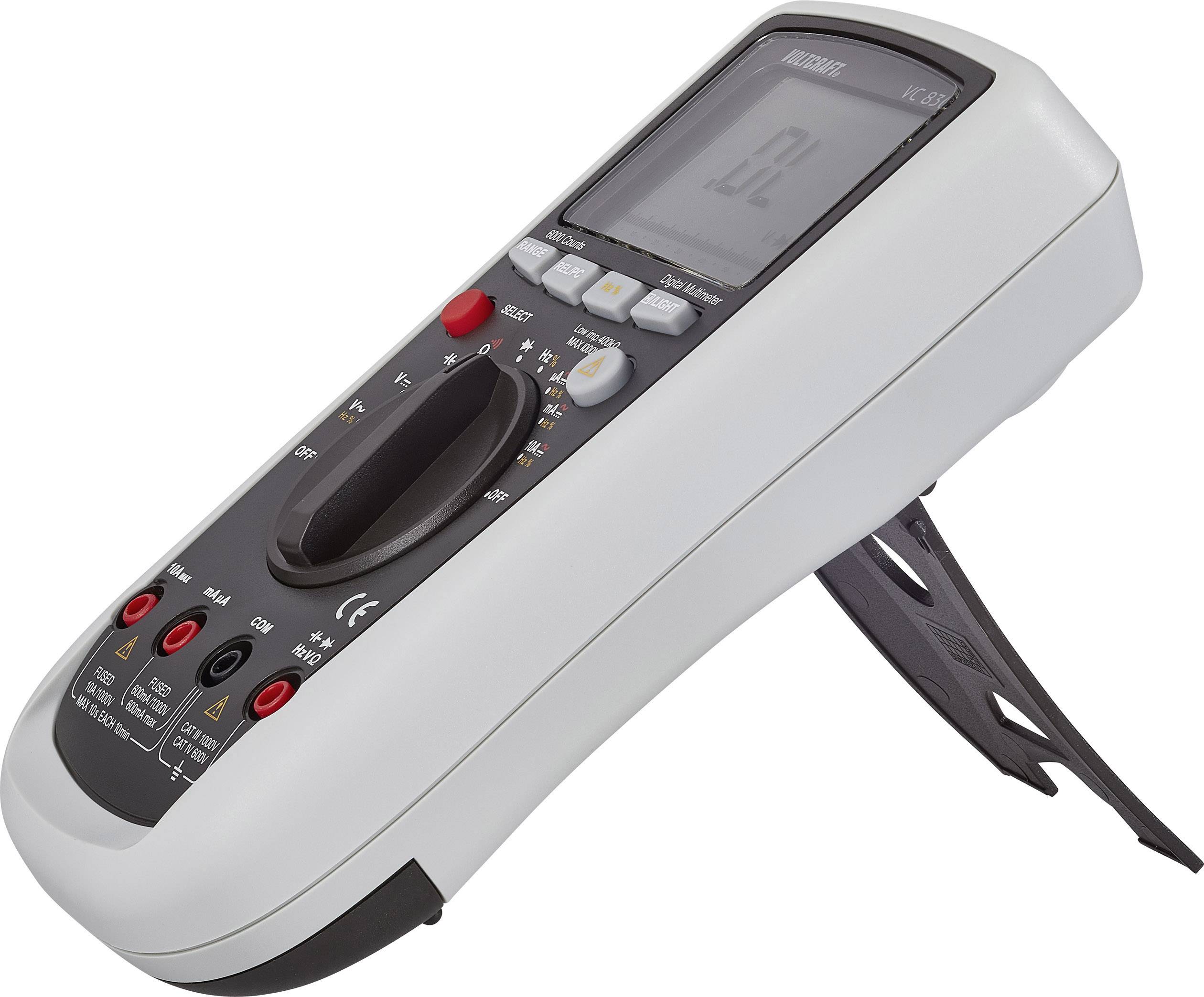 Ett digitalt multimeter som står på ett lutande underlag. Det visar en symbol på skärmen. Manöverknappar och anslutningar är synliga.