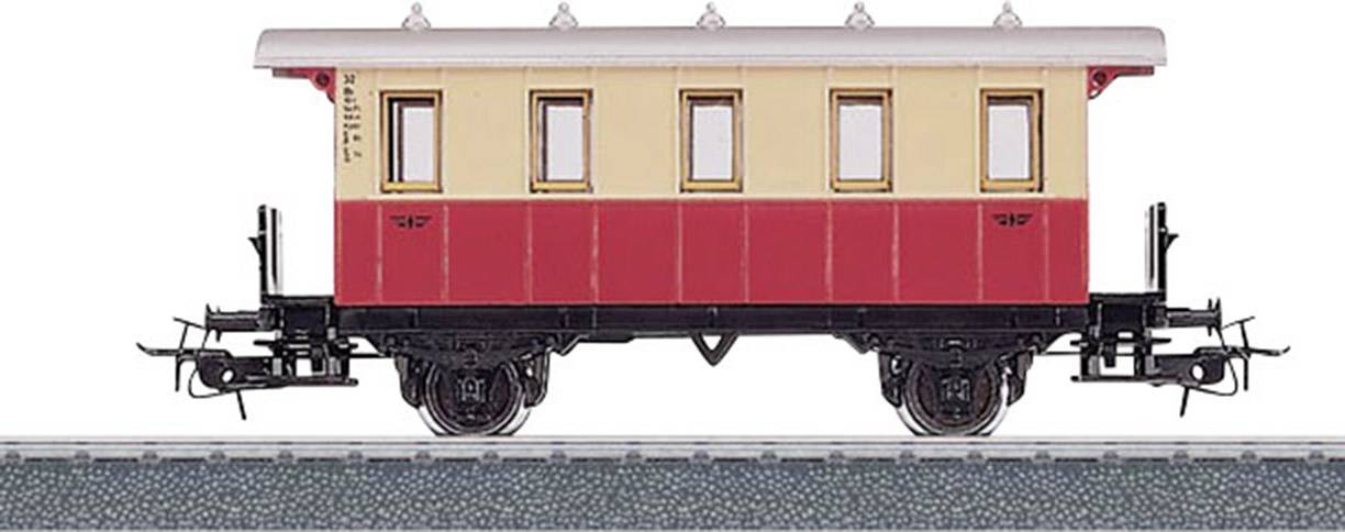 En modell av en historisk järnvägsvagn i rött och beige står på ett spår. Detaljerade hjul och kopplingar är synliga.