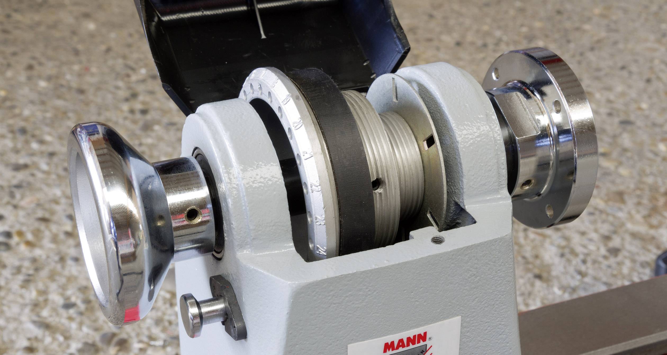 Ett silverfärgat chuck för en svarv placerat på en stenig bakgrund, lämpligt för fasthållning av arbetsstycken vid svarvningsprocesser.