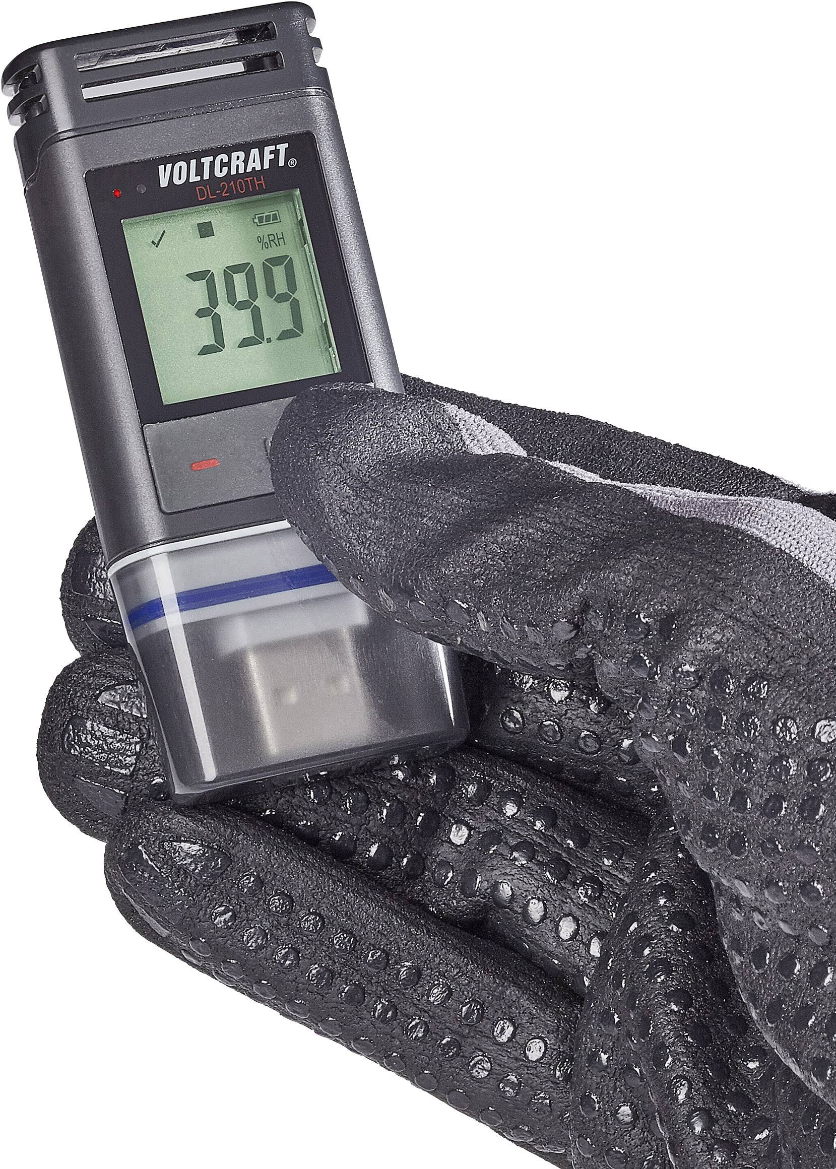 En hand med en svart handske håller en Voltcraft OL-230TH datalogger. Displayen visar '39.0'. Enheten används för temperaturmätning.