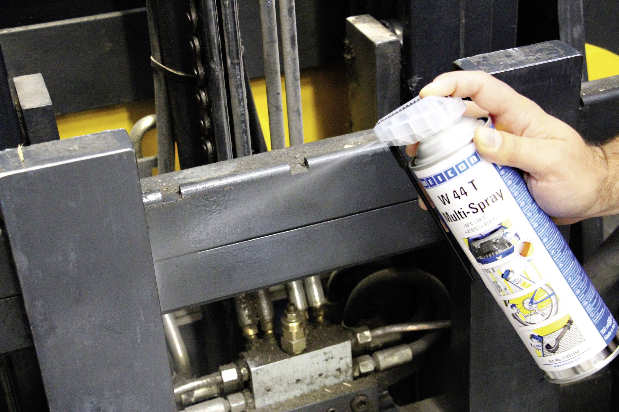 En hand sprayar multispray på maskinens metalldelar för underhåll och smörjning i syfte att säkerställa en friktionsfri funktion.