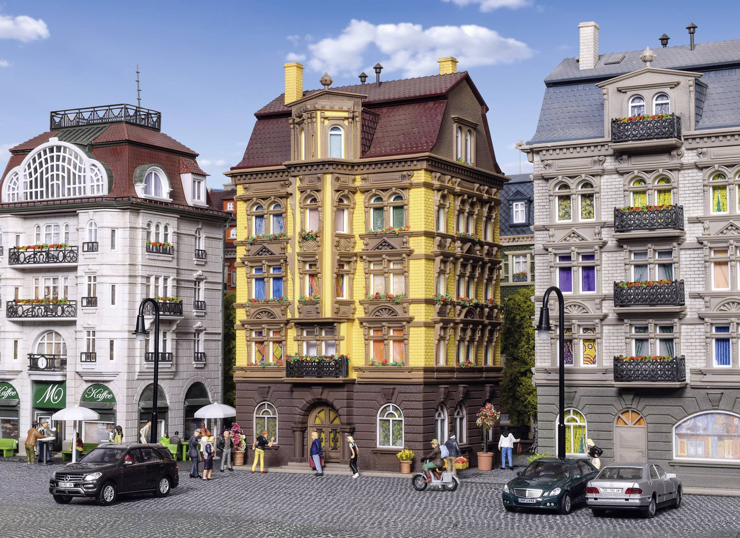 Gata med historiska byggnader, rikt dekorerade fasader, förbipasserande bilar och fotgängare; urbant, europeiskt stadslandskap.