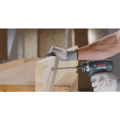 En person använder en blå, batteridriven Bosch slagborrmaskin för att borra ett hål i ett träbräde. Personen bär handskar.