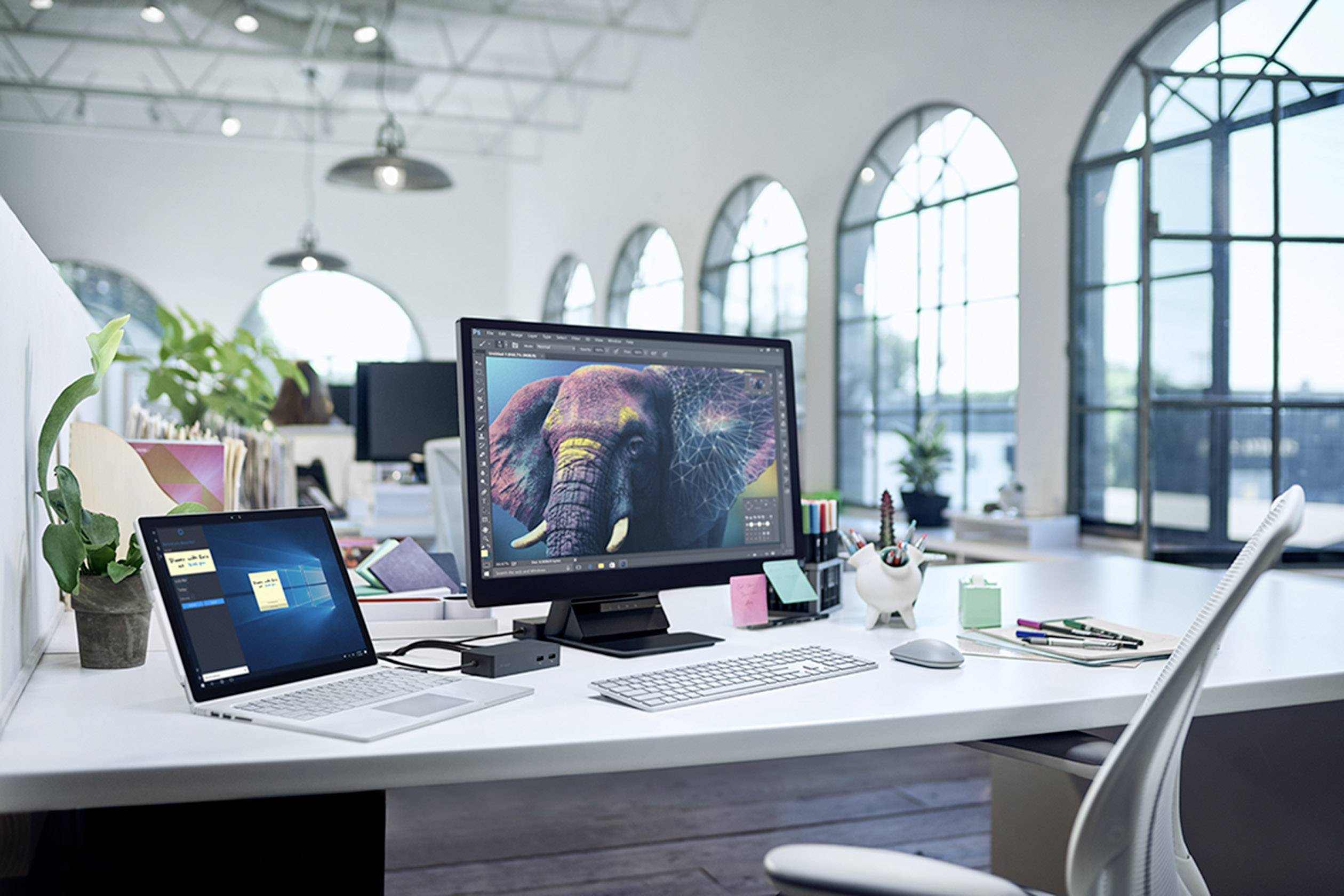 Ett modernt kontor med ett skrivbord där en laptop och en stor skärm står. Skärmen visar en bild på en elefant.
