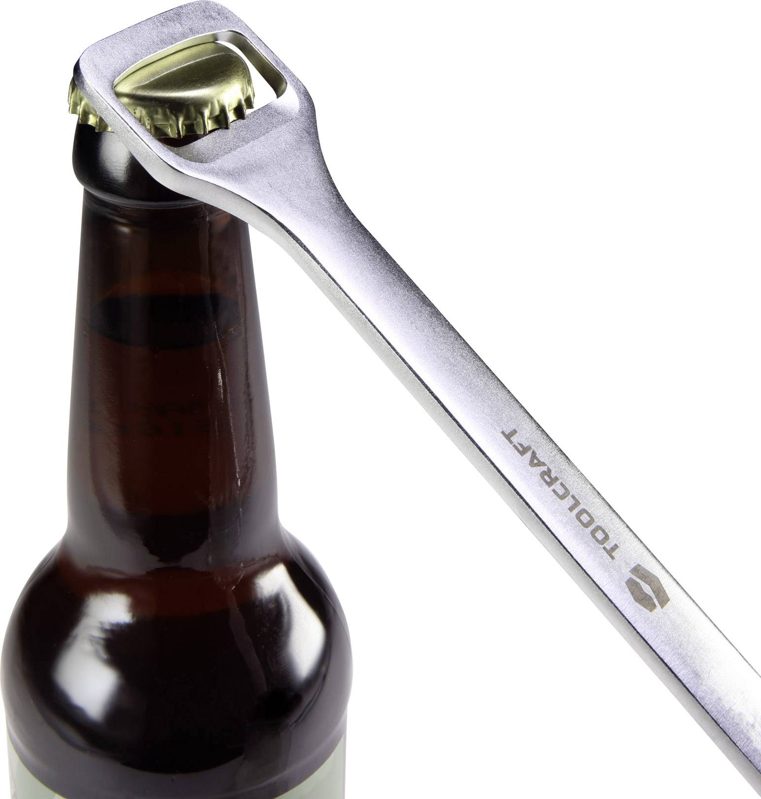 En metallisk flasköppnare tar bort kronkorken från en brun glasflaska.