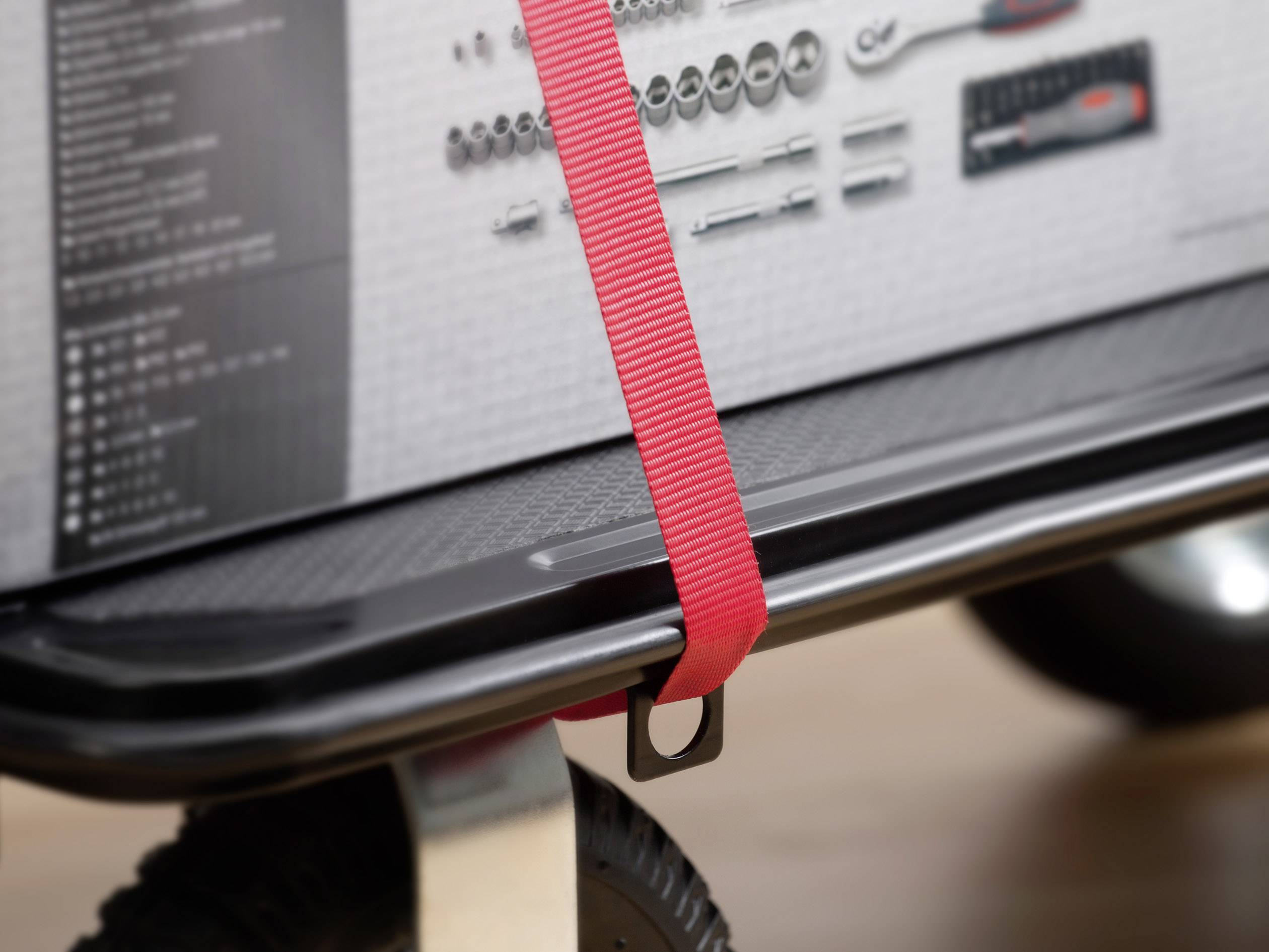 Röda spännband säkrar en låda med verktyg på en transportvagn.