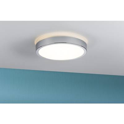 En rund, modern LED-taklampa med silverram lyser från ett vitt tak. Under den syns en turkos vägg.