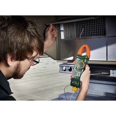 En man kontrollerar den elektriska spänningen i en anläggning med ett multimeter. Enheten visar '00.12'.