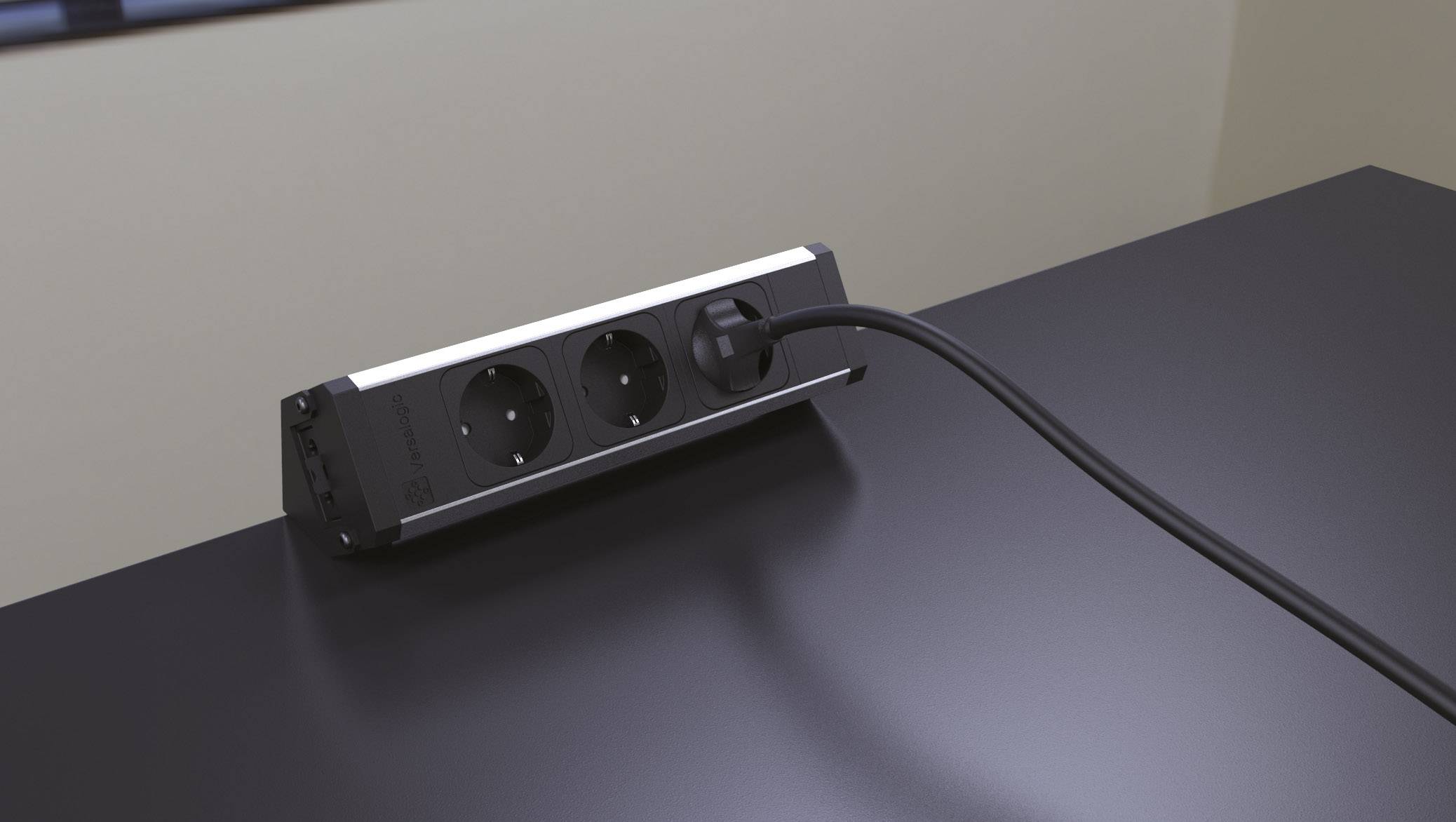 Ett svart kabel är anslutet till ett grenuttag med två platser på ett bord. Omgivningen ser modern ut.
