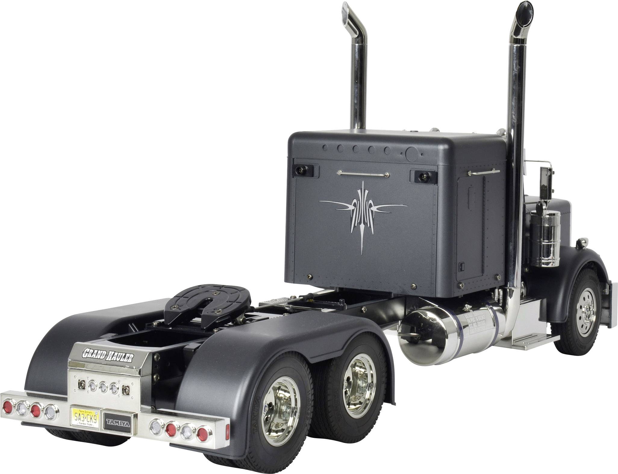 En svart lastbil med trailer står på en vit bakgrund. Ingen last eller tillkopplat släp syns. Imponerande avgasrör.