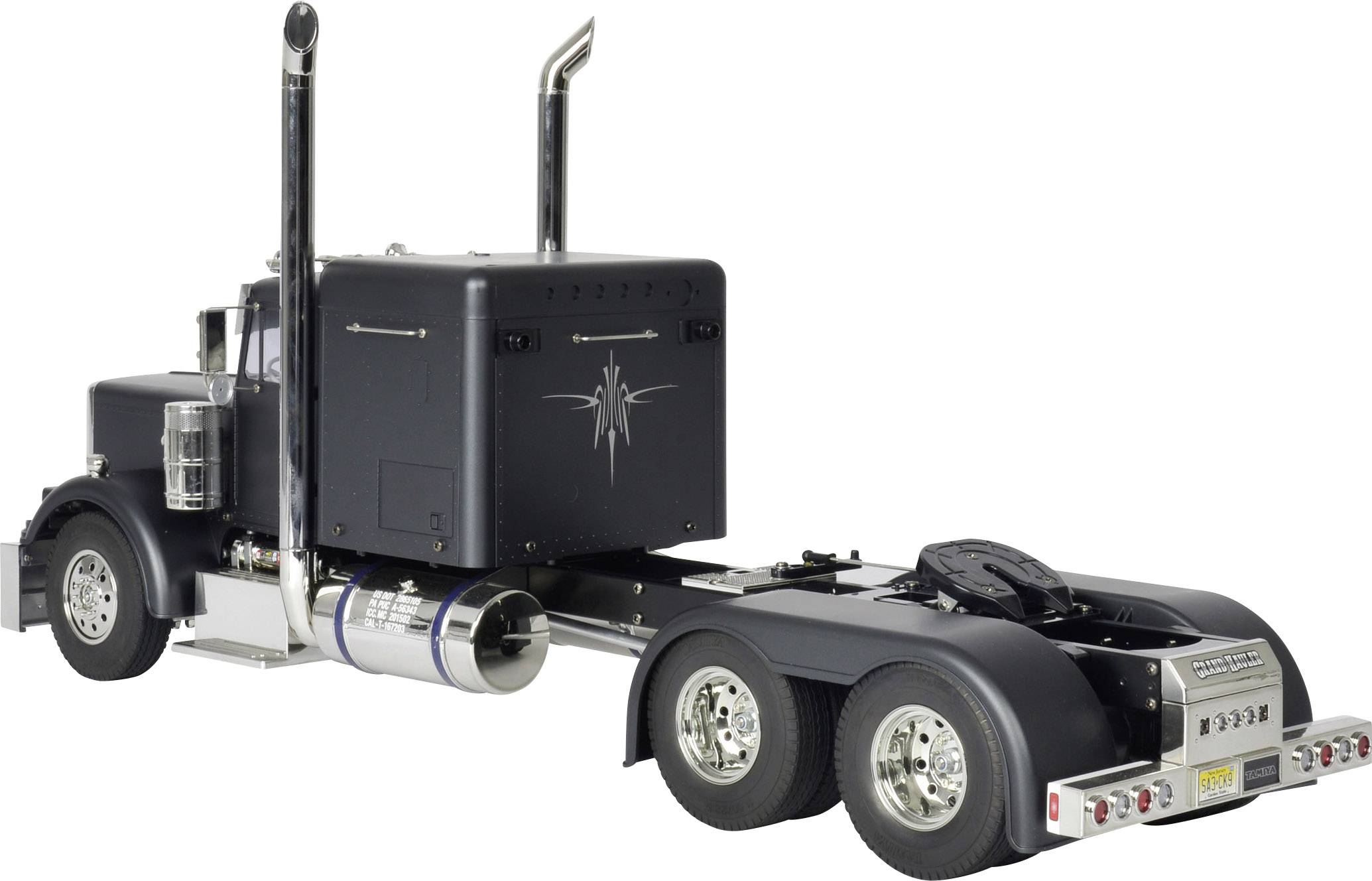 Svart lastbil utan trailer, sedd från sidan bakifrån, med silvriga detaljer, kromade avgasrör, två bakaxlar.