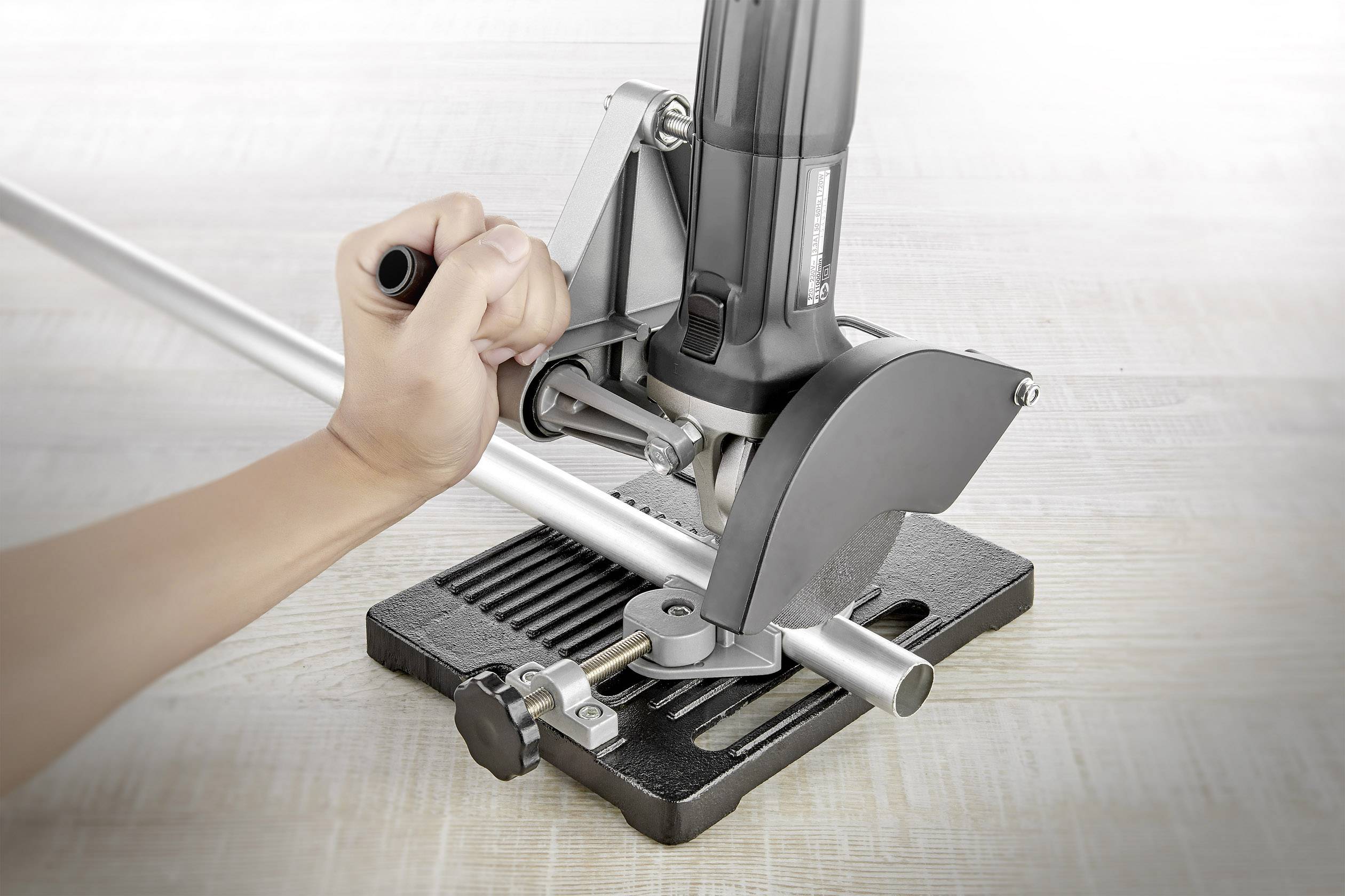 En person hanterar en metallsåg på ett arbetsbord och sågar ett silverfärgat metallrör. Sågen är fäst vid en bas.