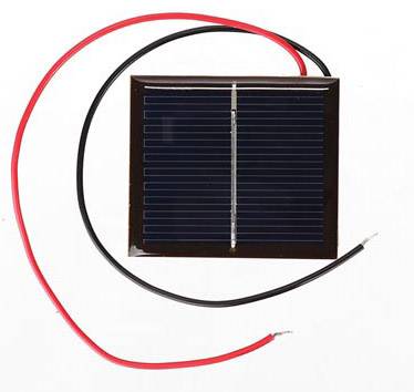Litet solpanel med två anslutna trådar, en röd och en svart, på vit bakgrund.