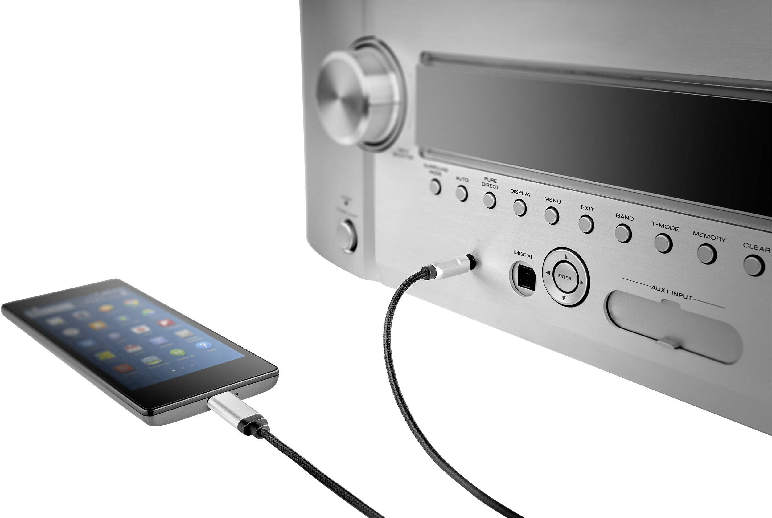 En smarttelefon är ansluten till en förstärkare via en audiokabel. Förstärkaren har flera knappar och ett stort volymhjul.