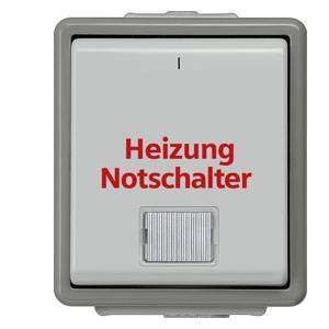 Fyrkantig grå switch med röd text 'Nödbrytare för värme', under den en vippströmbrytare.