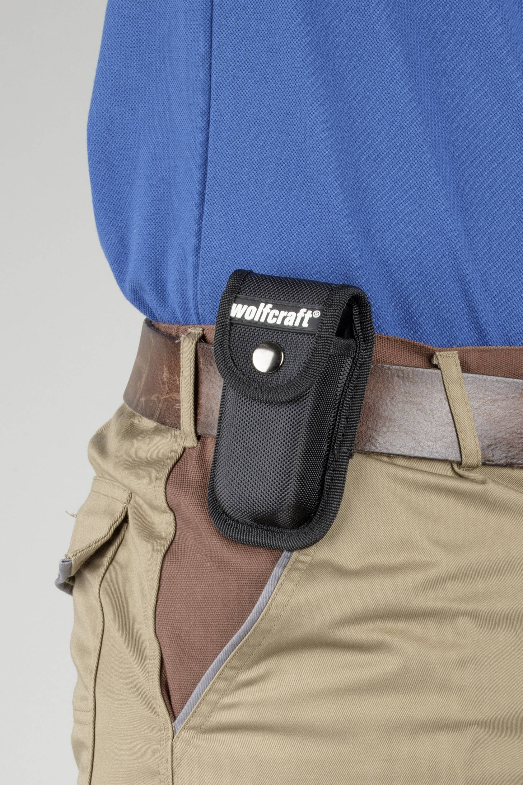 En person bär ett svart verktygsställ med påskriften 'wolfcraft' på ett brunt bälte.