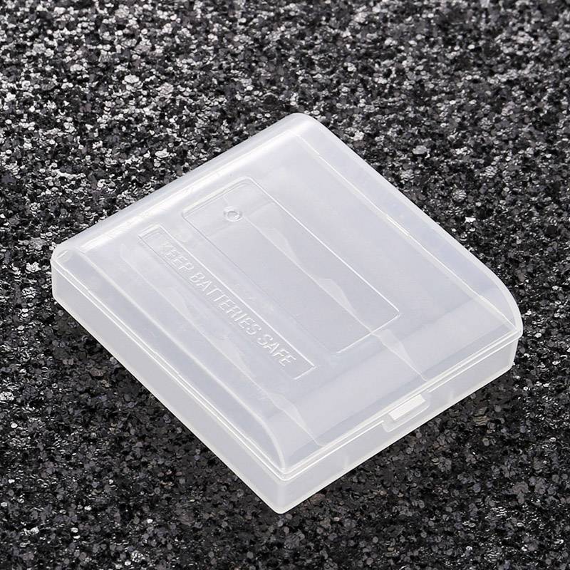 En transparent batterilådsbehållare på en mörk, kornig yta.