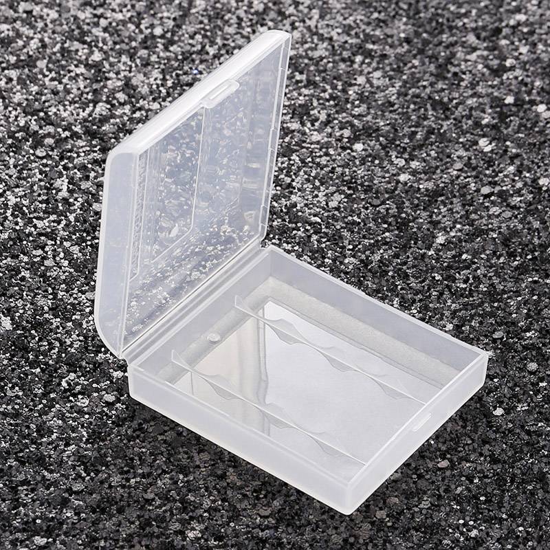 Liten, transparent plastlåda på grå, kornig bakgrund, öppen och tom.