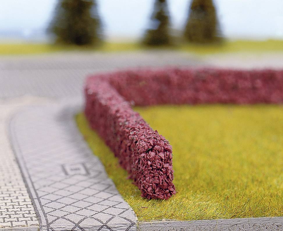 En modell av ett landskap med en häck av rött löv som avgränsar en gräsmatta längs en mönstrad gångväg.