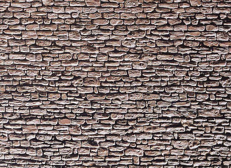 Tegelstenmur med ojämna, brunaktiga stenar. Stenarna varierar i form och storlek och är tätt placerade intill varandra.