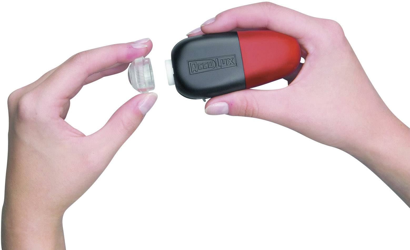 En hand håller en röd och svart enhet medan den andra handen tar bort det avtagbara locket.