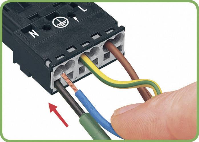 En person visar hur man för in trådar i en elektrisk klämma med olika färgade anslutningar.