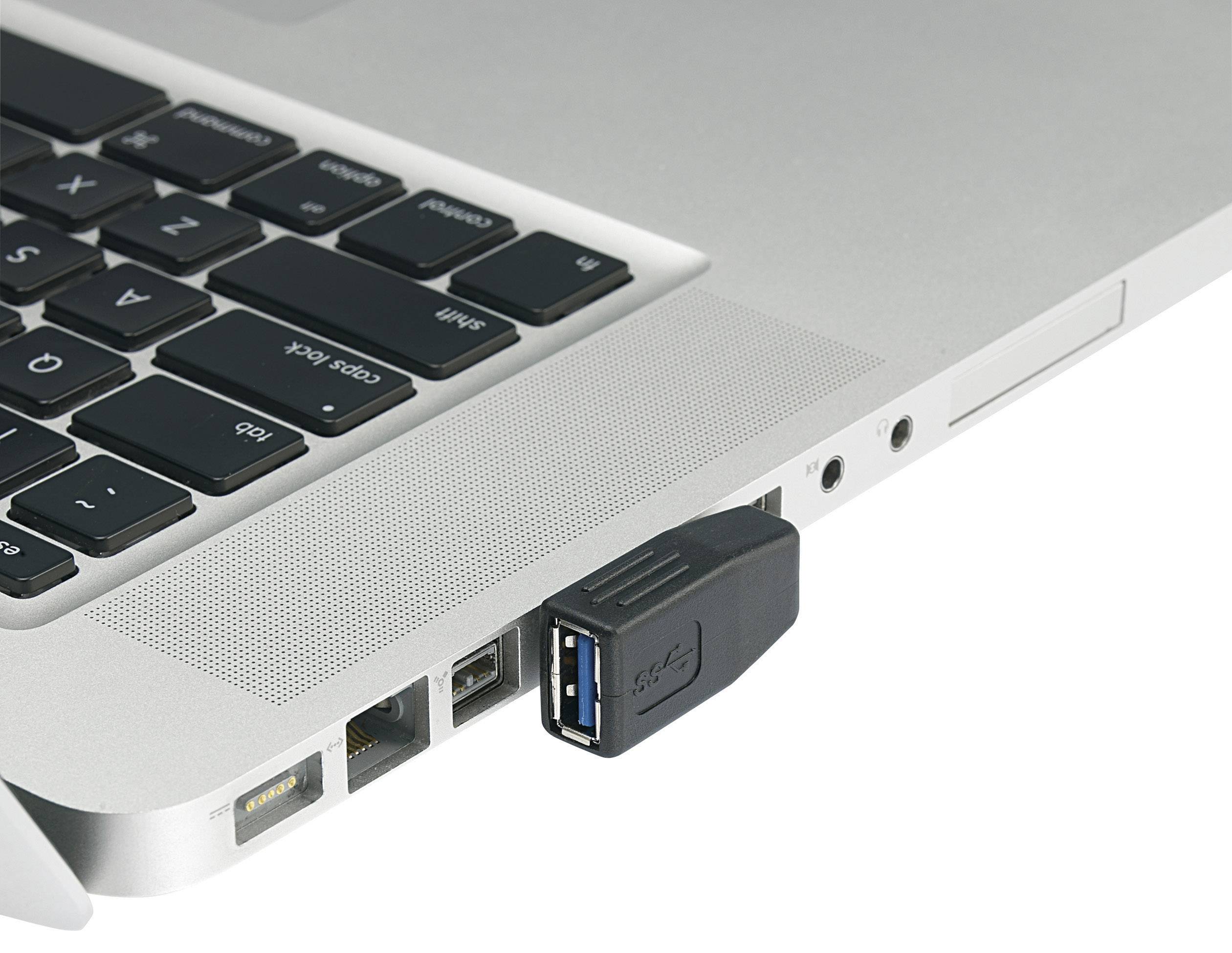 Ett USB-minne är instucket i en bärbar dator. Den bärbara datorn är silver och visar delar av tangentbordet och anslutningarna.