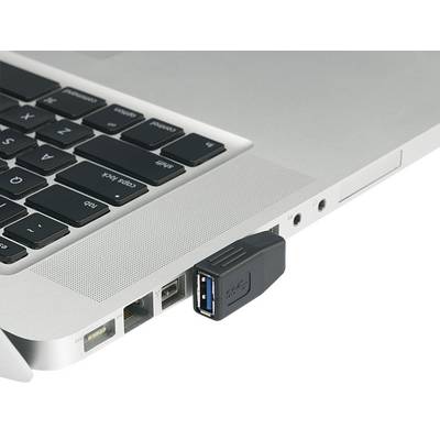 Ett USB-minne är instucket i en bärbar dator. Den bärbara datorn är silver och visar delar av tangentbordet och anslutningarna.