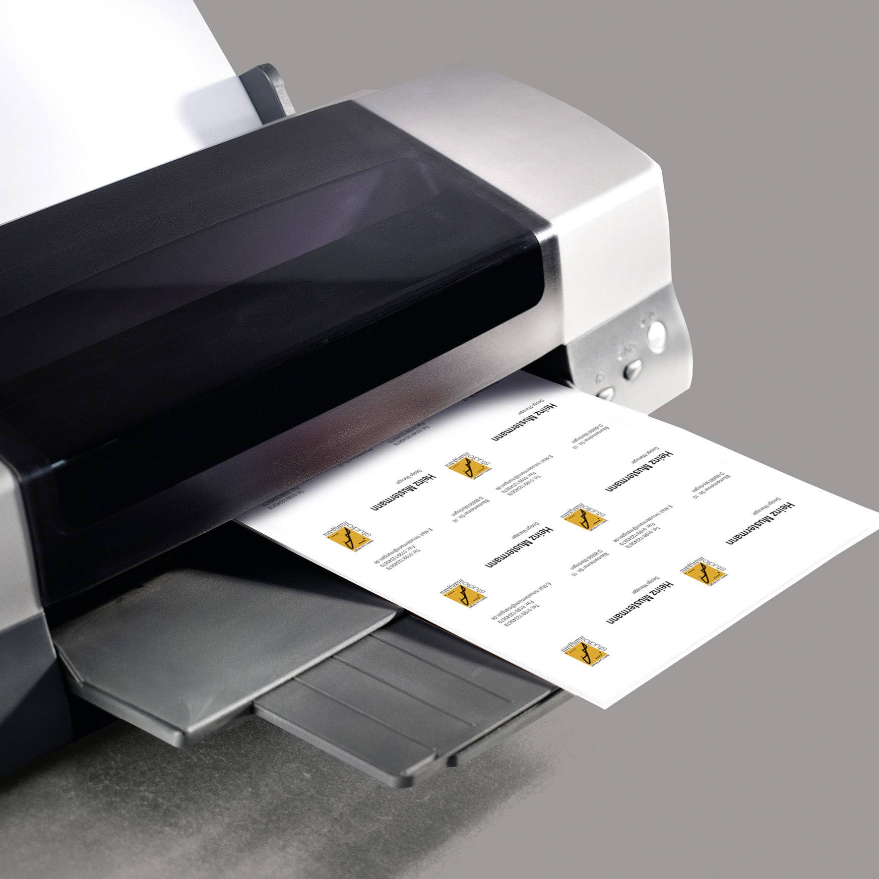 En skrivare skriver ut visitkort med texten 'John Smith'. Korten matas ut på ett vitt ark i ett ljust rum.