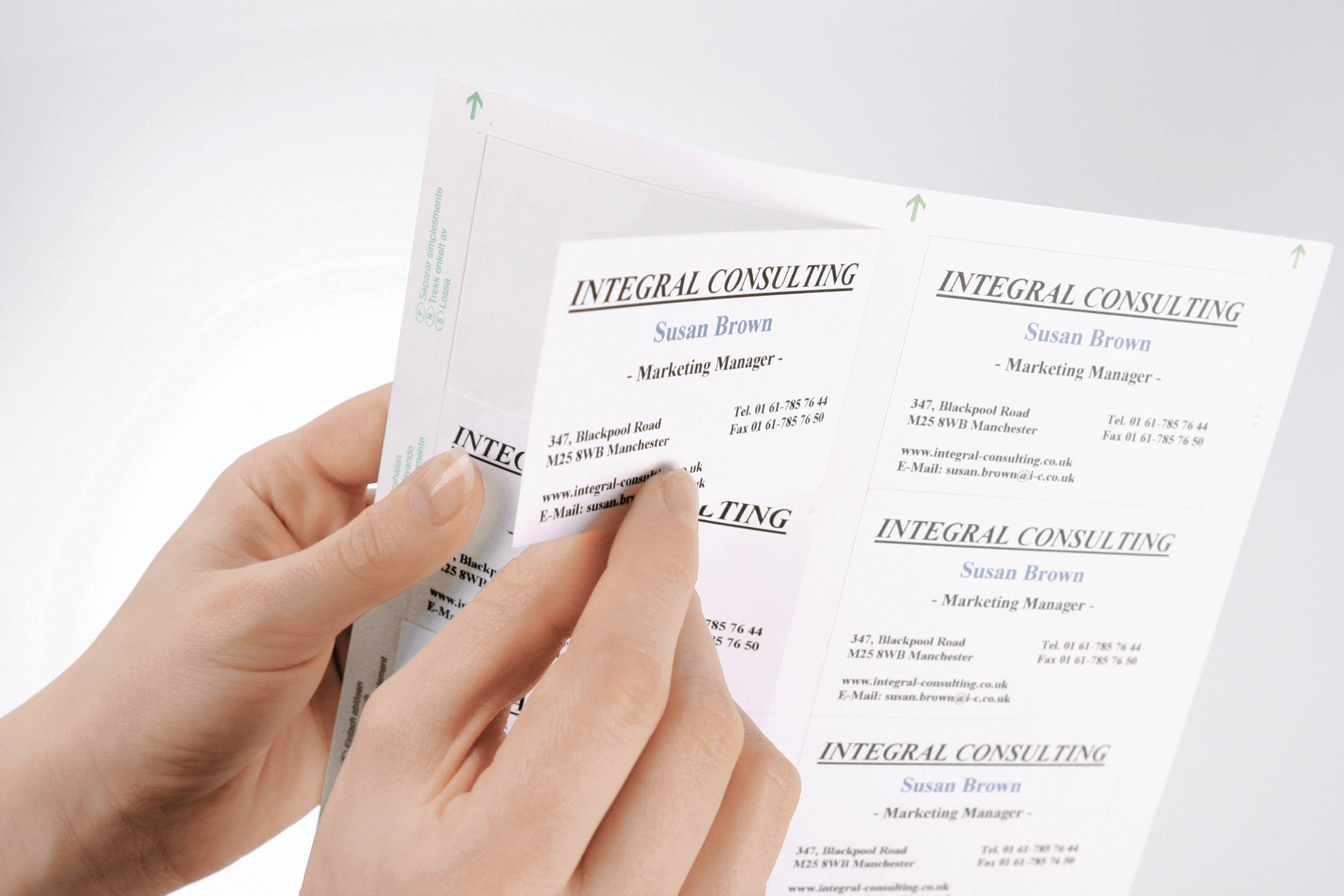 Två händer håller och bläddrar genom visitkort från ett företag som heter 'Integral Consulting'. Huvudkontakt: Susan Brown, marknadsföringschef.