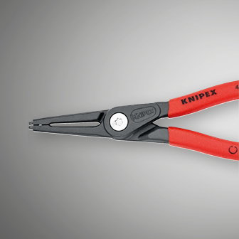 Billedet viser et nærbillede af en Knipex låseringtang med røde håndtag og grå kæber mod en sløret grå baggrund.