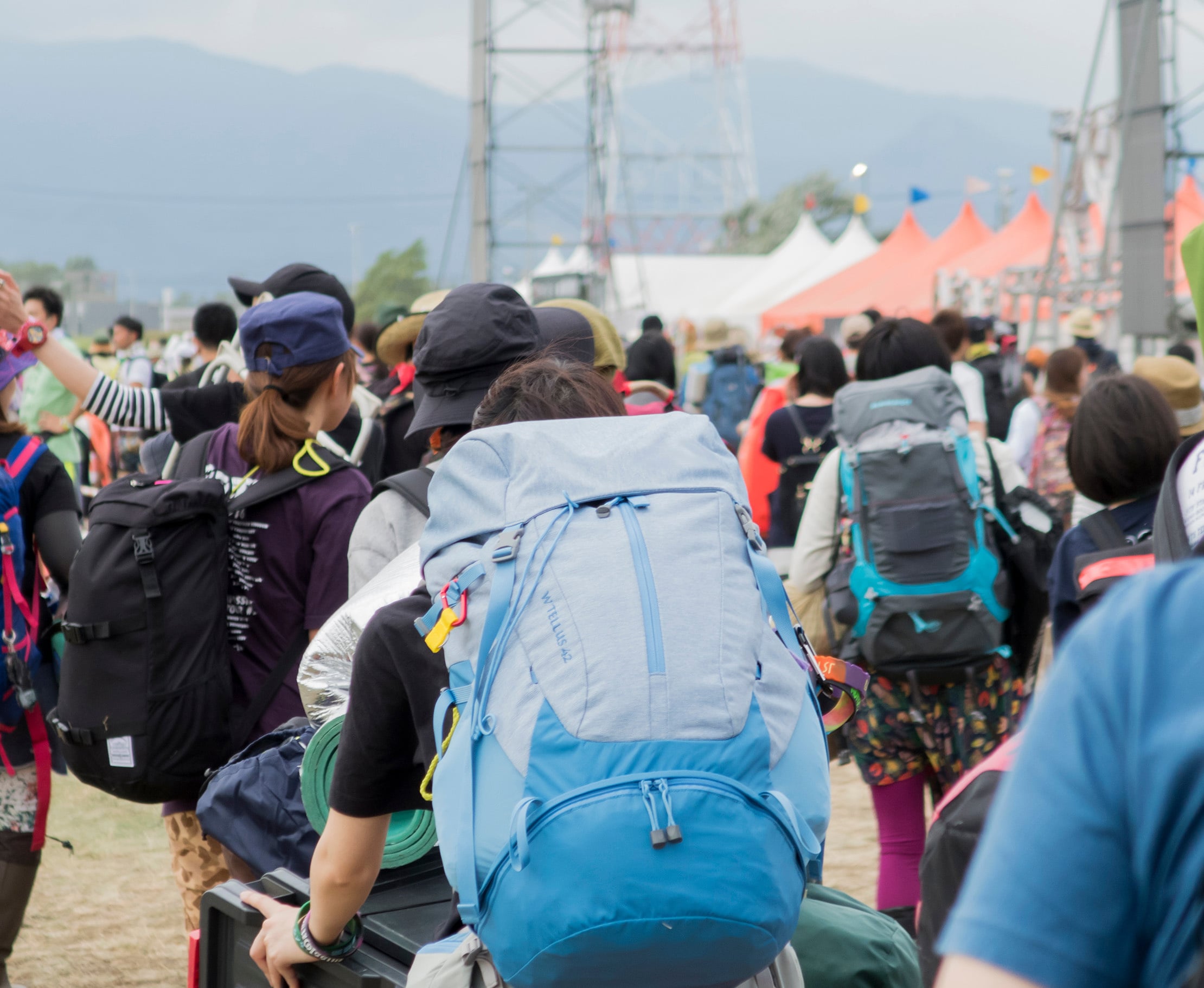 Eine große Gruppe von Festivalbesuchern mit Rucksäcken bewegt sich über ein Festivalgelände.