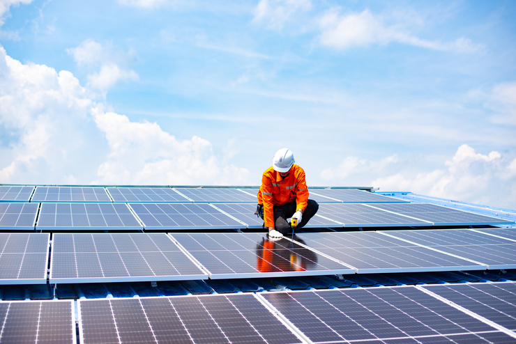 Techniker installiert Solarpanels auf einem Dach als Teil nachhaltiger Gebäudetechnik